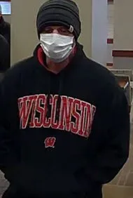 white male bank robber, 5’10” – 6’00”, medium build, wearing; a grey and yellow striped Carhartt beanie, black hoodie (red lining) with red WISCONSIN on the front,