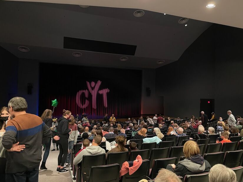 audience in theater with CYT projected on the curtain