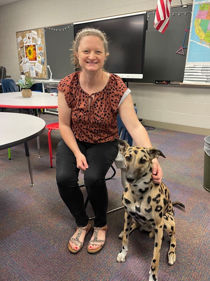 Female teacher in classroom with cheetah-colored dog