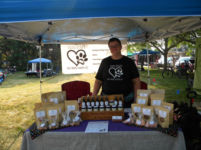 Vendor displays her home-made dog treats and balms at outdoor summer market.