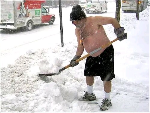 Shirtless man shoveling snow in shorts