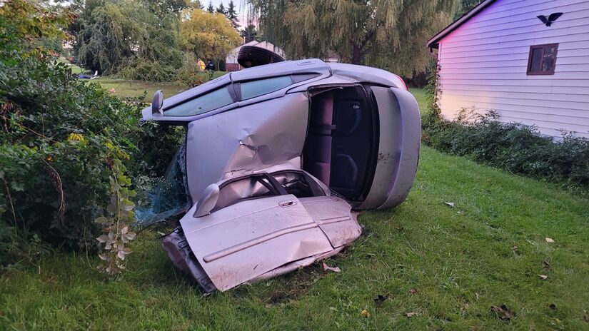 wrecked gray car on its side, with door torn off