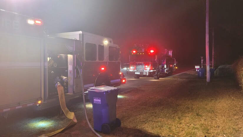 Two fire trucks at night with hoses