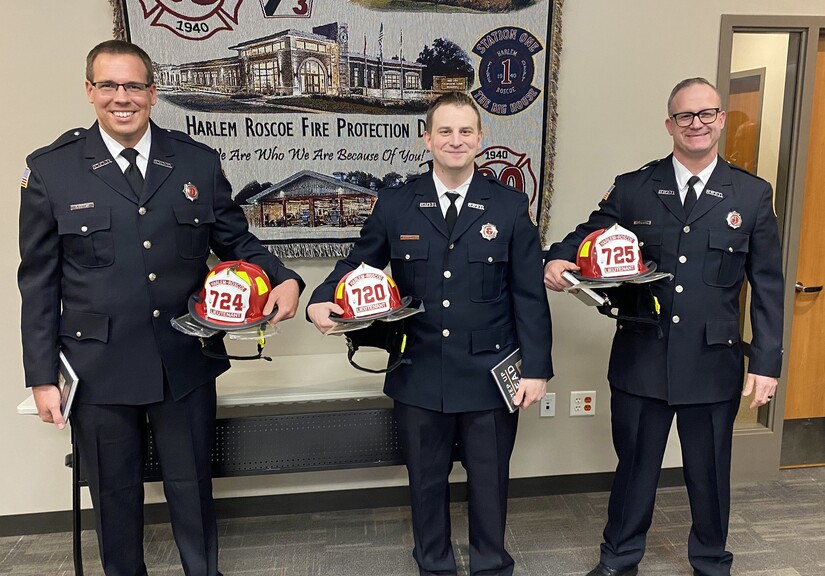 Three fire lieutenants holding their new helmets