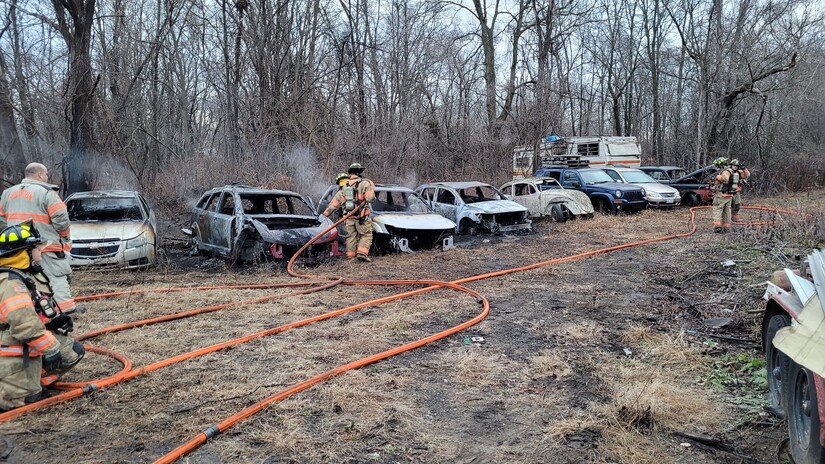 Burned salvage vehicles and firefighters with hose