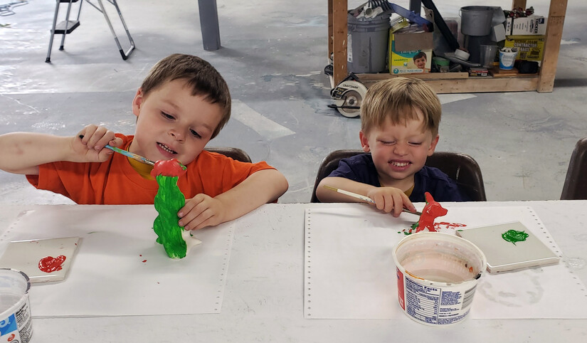 Two boys at a table painting ceramics with glaze