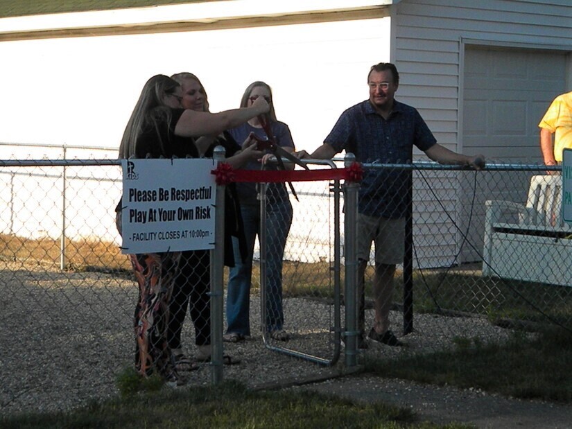 Ribbon cutting at chainlink gate to preschool playground