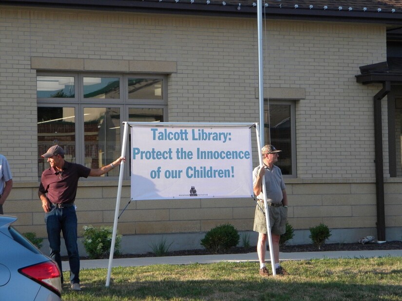 Anti-drag protesters hold a sign saying "Talcott Library: Protect the Innocence of our Children"