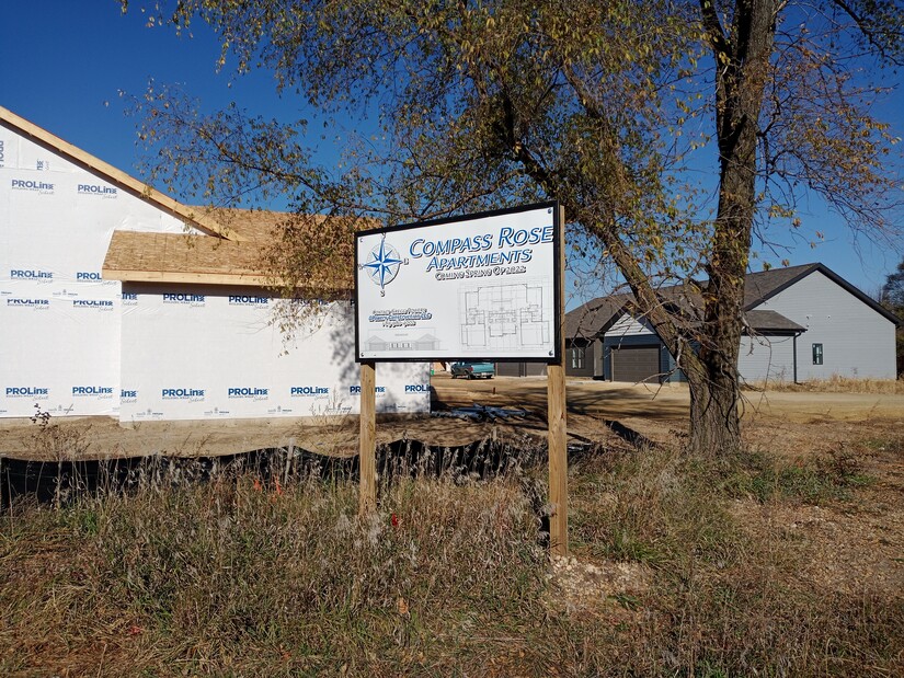 Duplex under construction, with sign "Compass Rose Apartments, coming spring of 2022, contact Gregg Powers, GPowers Construction LLC"