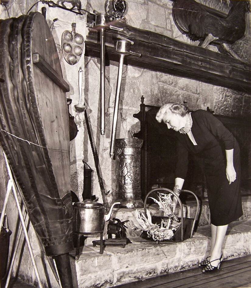 A 1950s woman in a hat inspects a fireplace at Wagon Wheel Resort, Rockton IL