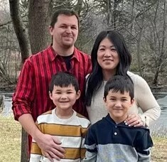 Father, mother, and two sons under trees near river