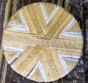 Death's Head button, wrapped with yellow, brown, and blue threads