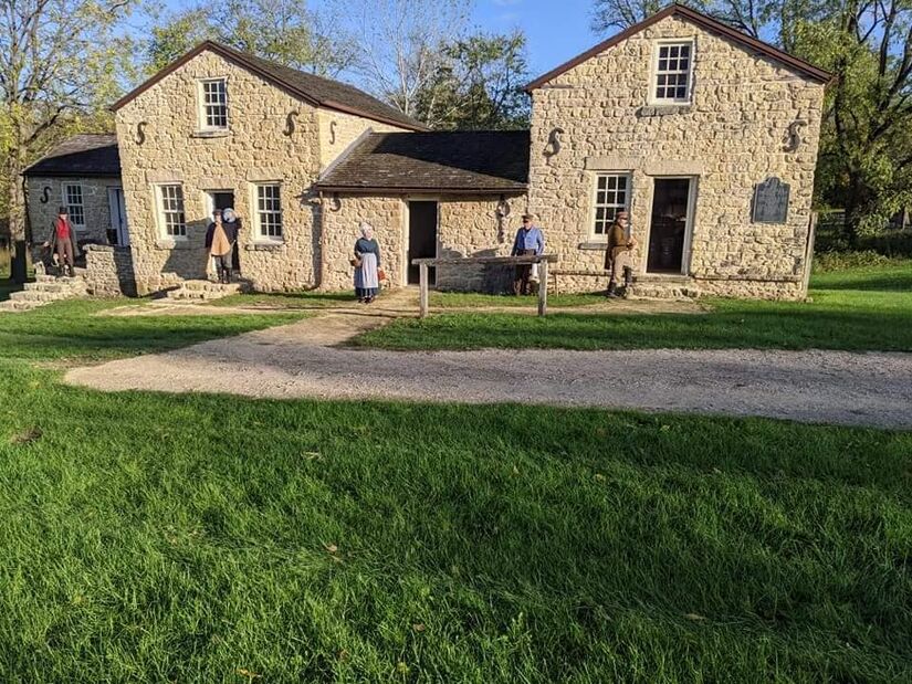 Whitman Trading Post (1846), two yellow stone buildings in Macktown Living History, Rockton, IL, with reenactors dressed in 1840s clothing